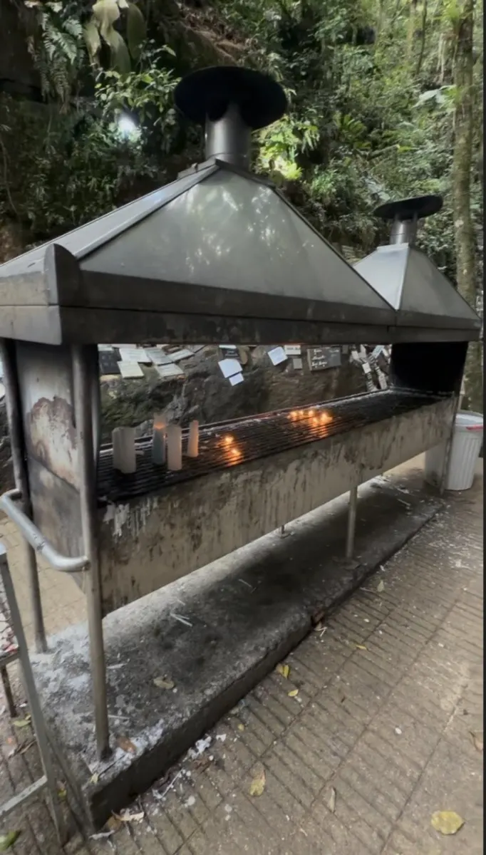 Suporte metálico de velas com coifas em meio à mata, na Gruta de Angelina (SC)
